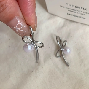 Detailed view of silver bow-knot stud earrings featuring a round white freshwater pearl