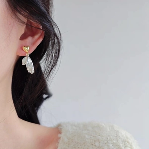 Elegant heart-shaped stud earrings with gold hearts and silver leaf tassels on model
