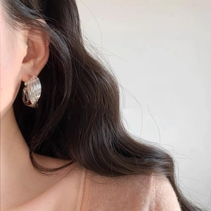 Close-up of a model wearing minimalist silver twisted multi-layer spiral hoop earrings