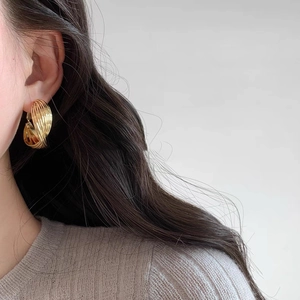 French style gold twisted hoop earrings with textured finish on female model