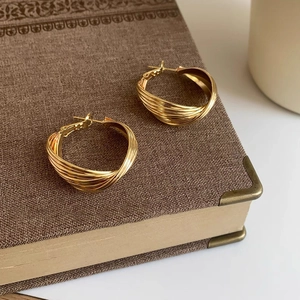 Close-up of golden twisted hoop earrings with textured spiral design on a vintage book