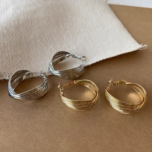 Macro shot of twisted metal hoop earrings in gold and silver finish with braided texture
