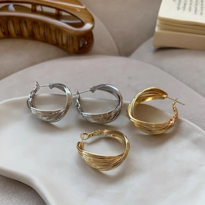 Detailed view of twisted gold and silver hoop earrings on a white ceramic tray