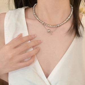 Détail d'un collier double épaisseur avec perles argentées et pendentif en cœur