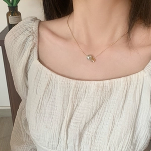 Gros plan d'un collier en or avec perle grise et zircon carré sur un mannequin