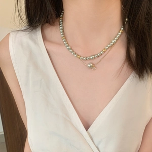 Gros plan d'un collier élégant à deux rangs avec perles gris-vert et accents dorés
