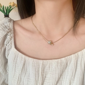 Détail d'un collier en or avec perle grise et zircon porté par un mannequin