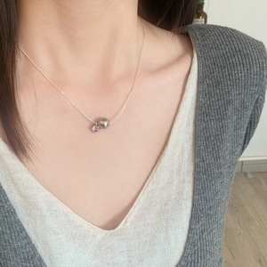 Collier élégant avec perle grise et zircon porté par un mannequin sous une lumière douce