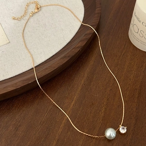 Détail du collier chaîne dorée élégant avec perle grise et pendentif en zircon clair