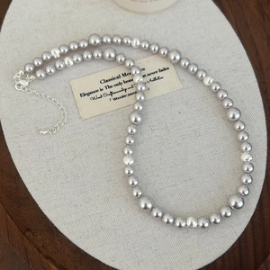 Détail du collier de perles gris-violet avec perles en métal argenté et fermoir mousqueton