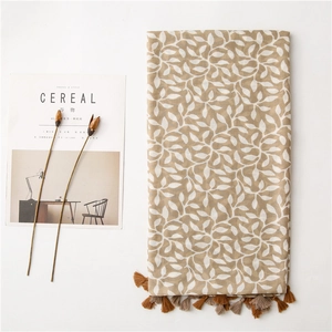 Detail of soft linen scarf with white leaf patterns and fringe tassels for sun protection