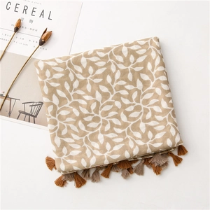 Detail of soft linen scarf featuring white leaf patterns and delicate fringed edges