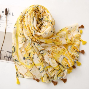 Detail of bohemian paisley print linen scarf with tassel fringe on a white surface
