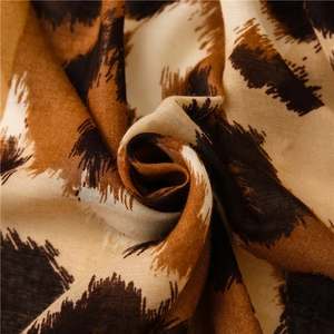 Close-up of leopard print scarf fabric showing soft weave and brown spotted patterns