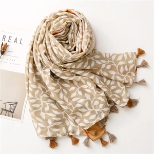 Detail shot of white grape leaf pattern and fringe on beige linen blend sun shawl