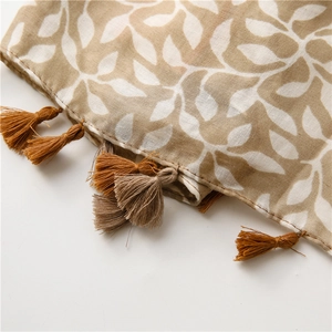 Detailed close-up of bohemian grape leaf pattern fabric with handmade tassels