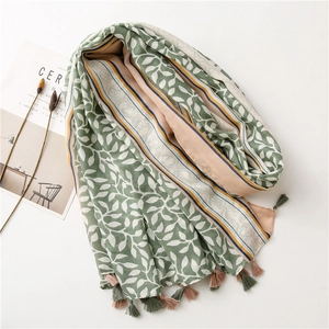 Close-up of lightweight linen shawl with green leaf pattern and colorful fringe accents