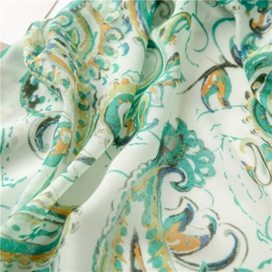 Detail of bohemian paisley print on lightweight linen-blend scarf with vibrant teal and orange