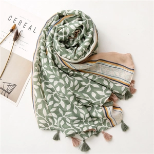 Detail of soft green cotton linen scarf with leaf print and colorful tassel edges