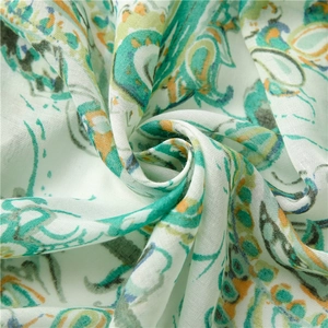 Close-up of lightweight linen scarf with green paisley print and woven texture