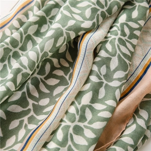 Detailed macro shot of soft cotton linen scarf with green grape leaf prints and fringe
