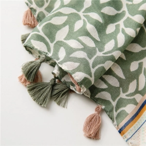 Detail of soft cotton linen scarf featuring green leaf patterns and colorful fringe tassels