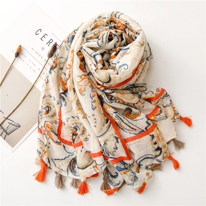 Flat lay of linen scarf with paisley print and orange tassels on a white background