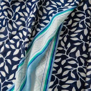 Detail of soft linen scarf showing blue grape leaf pattern and colorful stripe borders