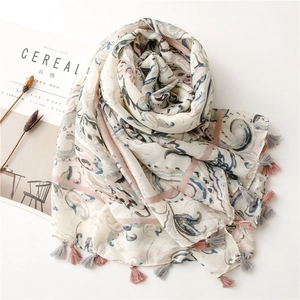 Flat lay of linen scarf with bohemian paisley print and delicate pink fringe tassels