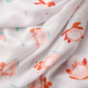 Macro detail of breathable cotton scarf featuring orange and pink floral print texture