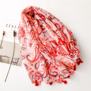 Detail of pink cotton linen scarf featuring orange paisley prints and red tassels