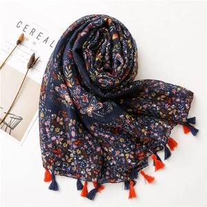 Detail of floral butterfly print scarf with elegant orange and blue tassels on edges