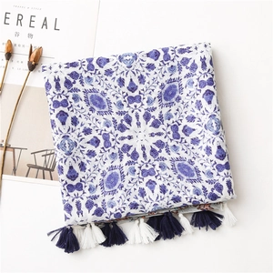 Detailed view of floral cotton linen scarf with blue fringes on white surface