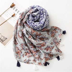 Detail shot of light grey linen scarf with blue floral prints and tassel fringe accents
