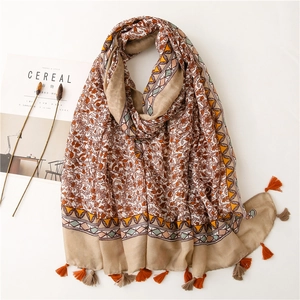 Macro detail of cotton-linen scarf with retro floral print and orange fringe tassels