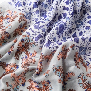 Detailed close-up of blue floral cotton linen scarf with soft folds and fringe edges