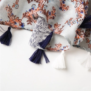 Close-up of blue floral cotton linen scarf with vintage prints and woven fringe tassels
