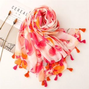 Close-up of floral print cotton scarf with pink and orange tassels on white background