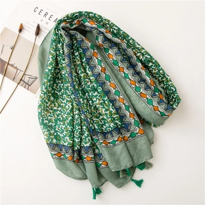 Detail of green floral linen scarf with geometric border and fringe tassels