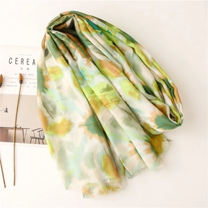 Detail of lightweight scarf with watercolor print and soft fringed edges on a desk