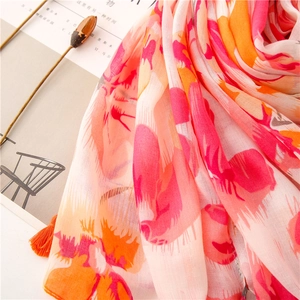 Detail of floral print scarf with orange tassels and lightweight translucent fabric