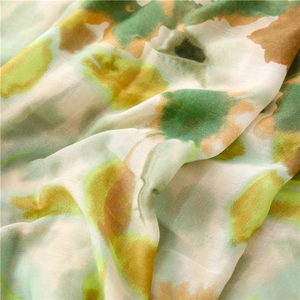 Close-up of soft lightweight scarf fabric with abstract watercolor floral print in green