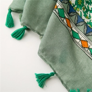 Detail of floral and geometric patterns on a grey-green cotton-linen shawl with tassels