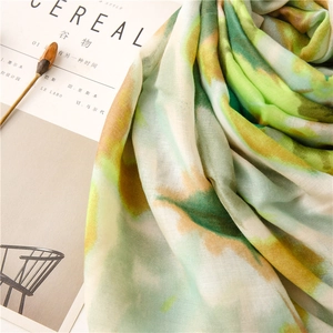 Detail of artistic tie-dye scarf with green and yellow ink patterns on soft fabric