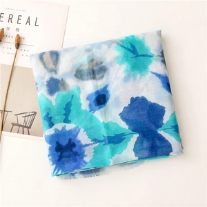 Detail of blue watercolor floral scarf with frayed edges styled next to a magazine