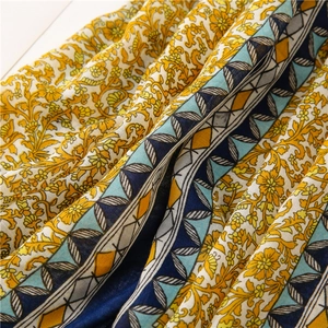 Detail of yellow floral cotton linen scarf with blue geometric borders and tassels