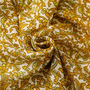 Detailed close-up of floral print fabric with yellow scrolls and soft linen texture