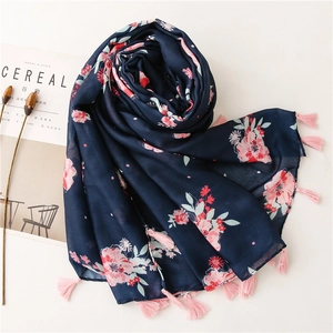 Detail of floral navy cotton linen scarf with pink tassels next to lifestyle magazine
