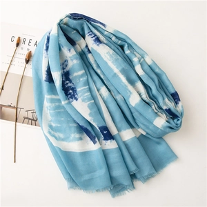 Macro shot of blue tie-dye cotton linen scarf with soft fringe edges and fabric texture