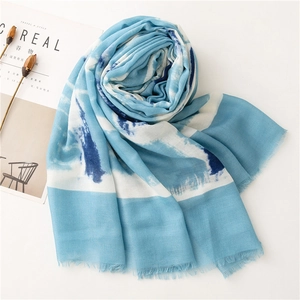 Detailed close-up of light blue and white watercolor printed scarf with fringe edges